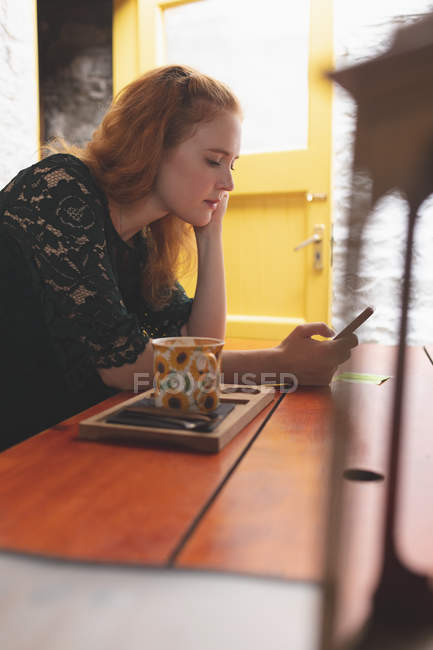 Rothaarige Frau benutzt Handy im Café — Stockfoto
