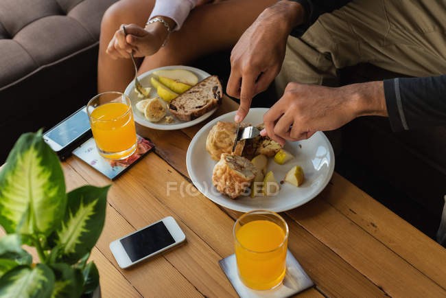 Media sezione di coppia che ha cibo in soggiorno a casa — Foto stock