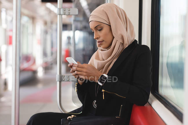 Hijab woman using mobile phone while travelling in train — Stock Photo