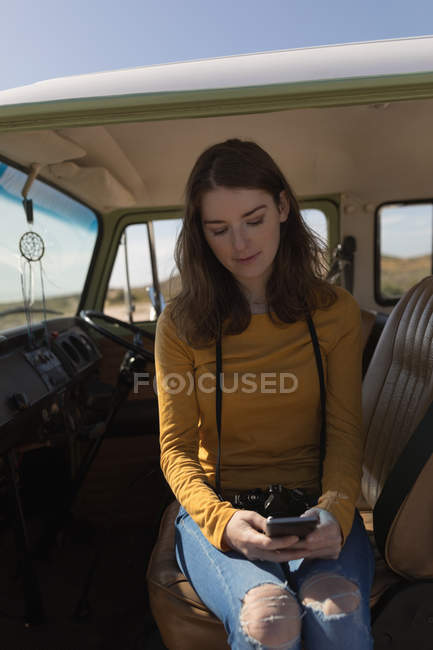 Woman using mobile phone in van on road trip — Stock Photo