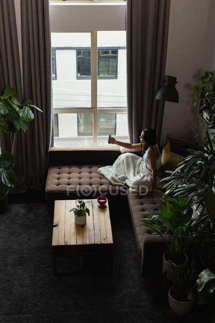 Donna che prende selfie sul cellulare in soggiorno a casa — Foto stock