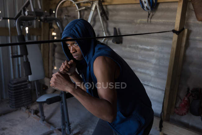 Boxeur masculin déterminé pratiquant la boxe dans un studio de fitness — Photo de stock