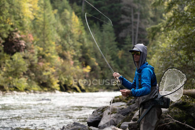 Pesca da mosca do pescador no rio em um dia ensolarado — Fotografia de Stock