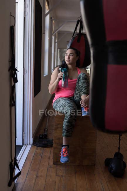 Thoughtful female boxer having water in fitness studio — Stock Photo