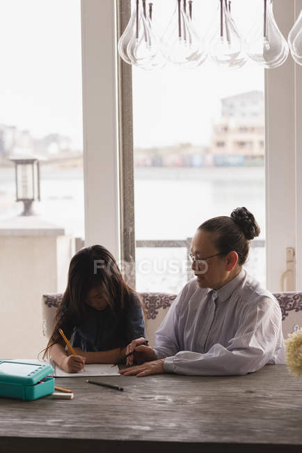 Grandmother and granddaughter drawing sketch on dining table at home — Stock Photo