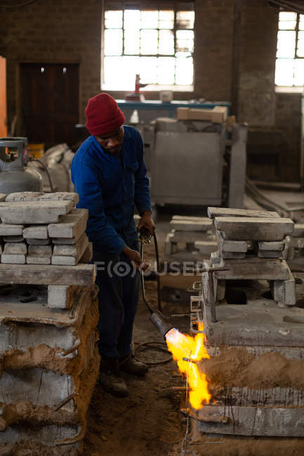 Worker heating furnace with flaming torch in foundry — Stock Photo