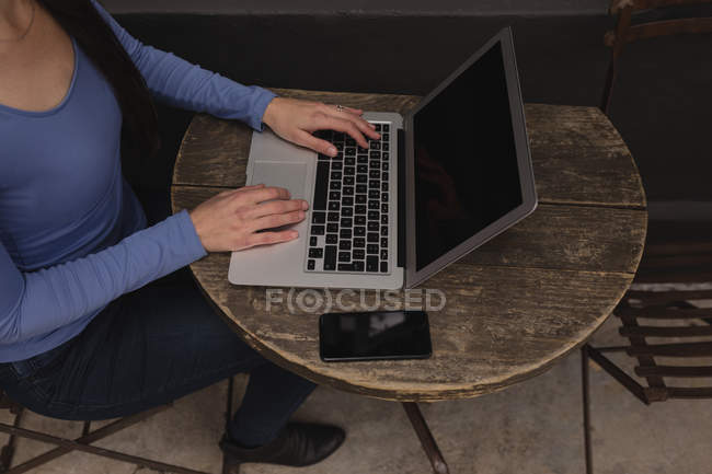 Section basse de la femme en utilisant un ordinateur portable dans un café extérieur — Photo de stock
