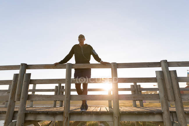 Low angle view of male athlete standing on pier — Stock Photo