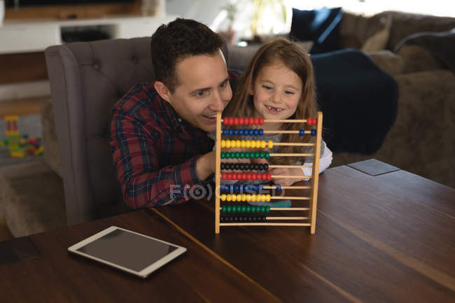 Pai brincando de ábaco com sua filha na sala de estar em casa — Fotografia de Stock