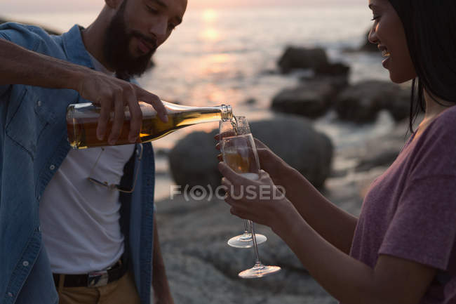 Pareja romántica tomando champán cerca del mar - foto de stock