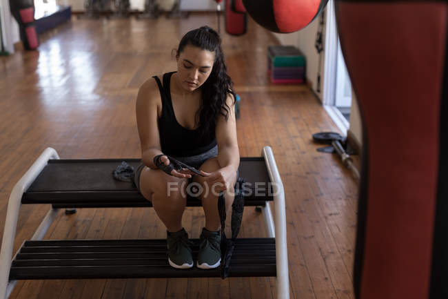 Young female boxer wearing hand wrap in fitness studio — Stock Photo
