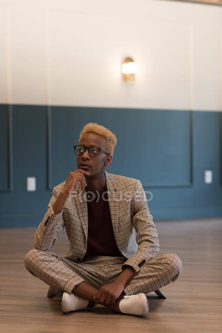 Homme d'affaires réfléchi assis sur le sol dans le bureau — Photo de stock