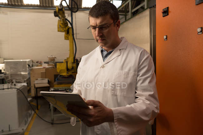 Robotic engineer using digital tablet in warehouse — Stock Photo