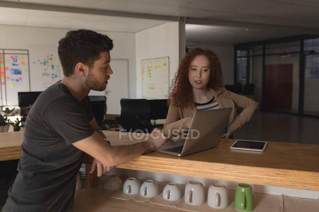 Руководители обсуждают за ноутбуком в офисе — стоковое фото