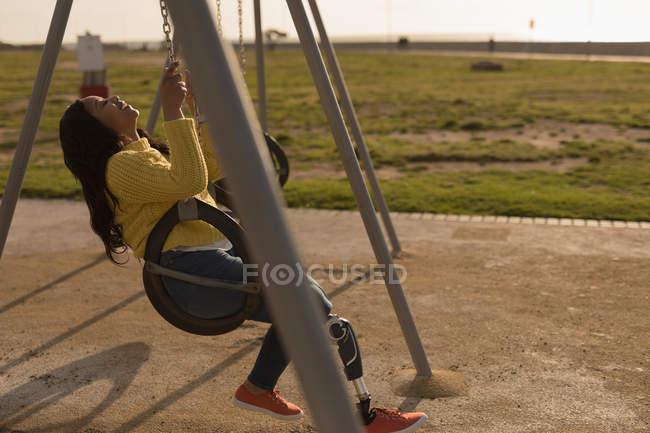 Felice donna disabile che gioca sull'altalena parco giochi — Foto stock