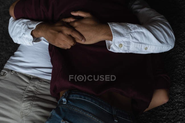 Seção média de casal relaxante no chão em casa — Fotografia de Stock