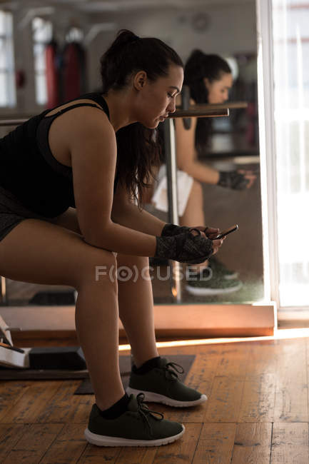 Вид збоку на боксерку, що використовує мобільний телефон у фітнес-студії — стокове фото