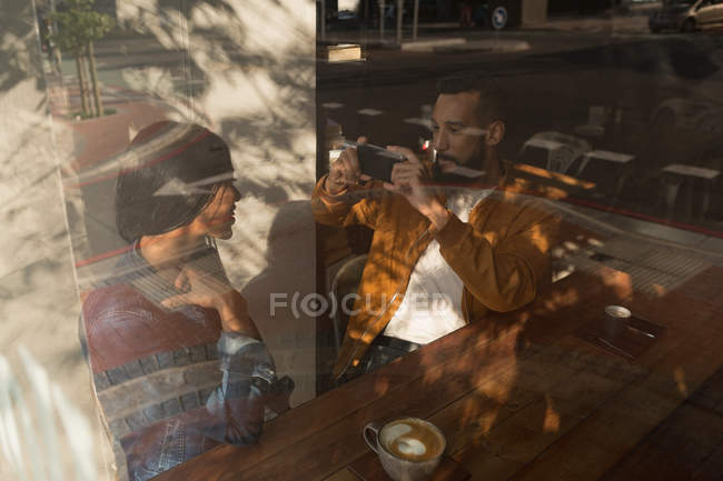 Smart man taking photo of woman in cafe — Stock Photo