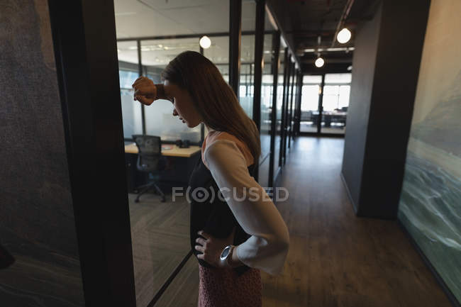 Расстроенная женщина-руководитель, стоящая в коридоре в офисе — стоковое фото