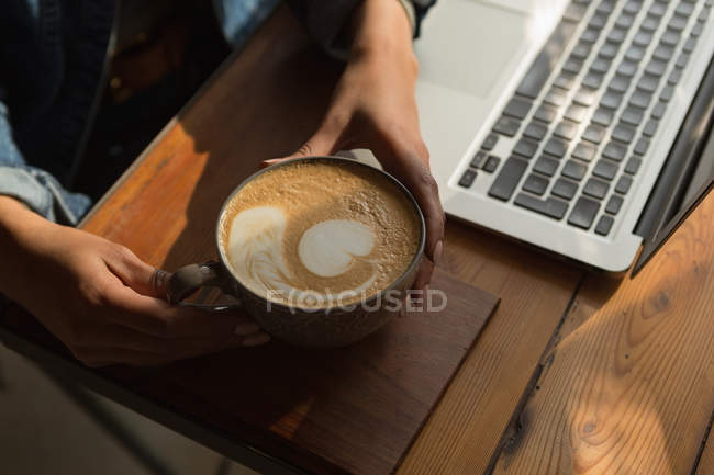 Primo piano della donna che tiene una tazza di caffè nel caffè — Foto stock