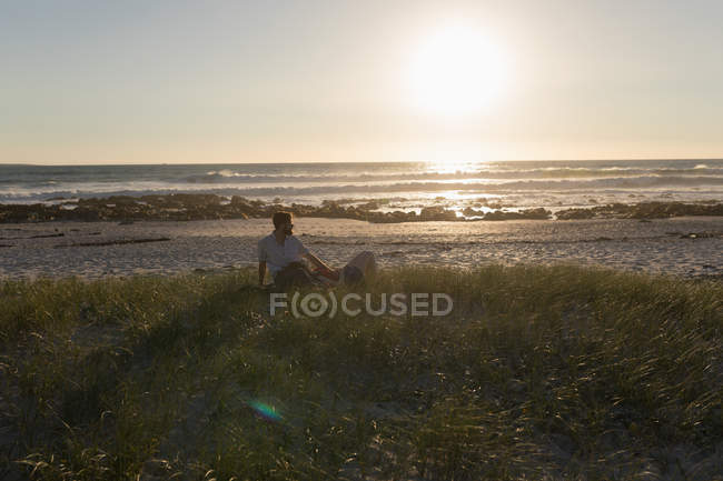 Woman lying on man's leg at beach during sunset — Stock Photo