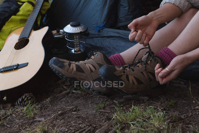 Primo piano della donna che indossa le scarpe al campeggio — Foto stock
