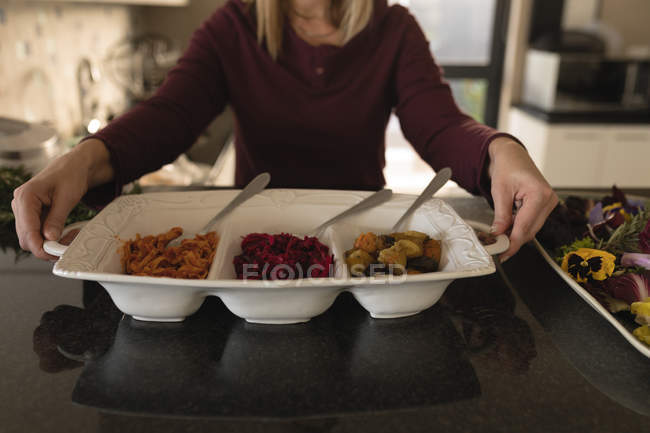 Mid section of woman holding food tray in kitchen at home — Stock Photo
