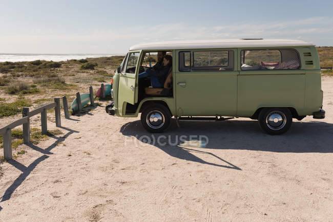 Pareja usando teléfono móvil en vehículo cerca de la playa - foto de stock