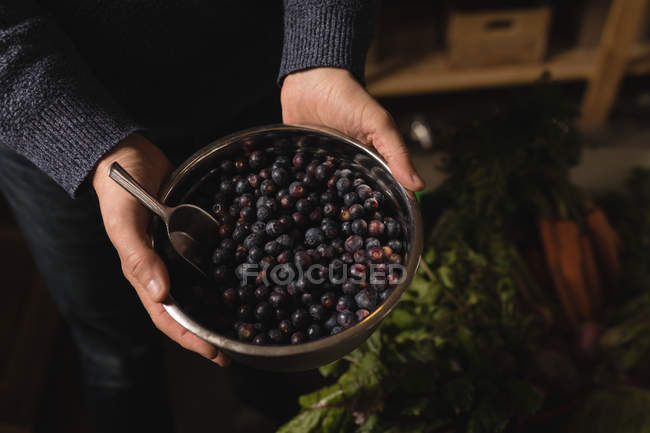 Mid section of man holding bowl of blueberries in supermarket — Stock Photo