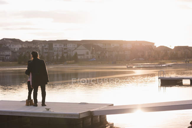 Rear view of grandmother and granddaughter standing on pier near lake side — Stock Photo