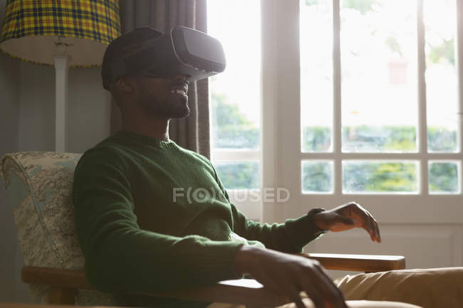 Uomo che utilizza cuffie realtà virtuale a casa — Foto stock