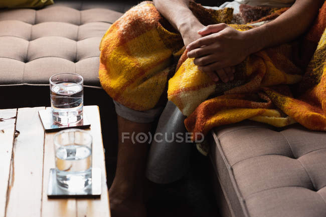 Low section of man sitting on sofa in living room — Stock Photo