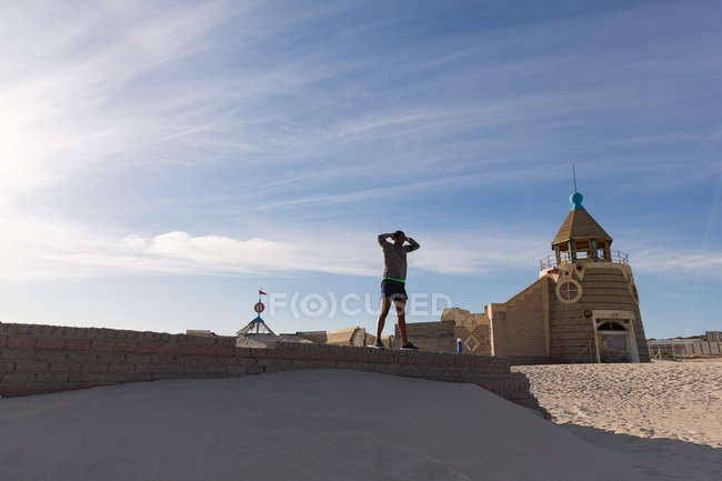 Männlicher Athlet trainiert auf umgebender Mauer in Strandnähe — Stockfoto