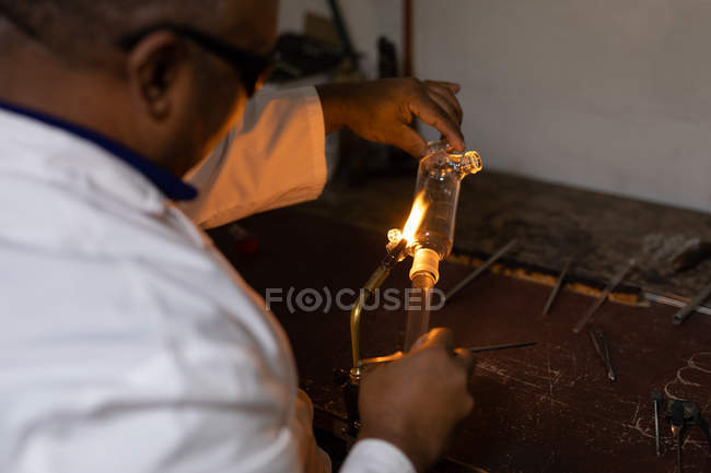 Рабочий мужчина с помощью сварочной горелки на стекольном заводе — стоковое фото