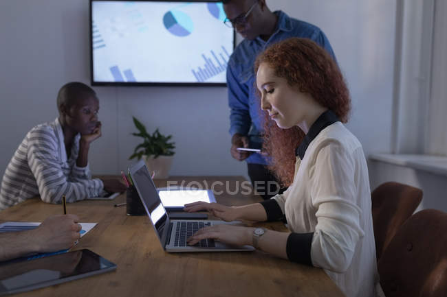 Female executive using laptop in conference room at office — Stock Photo