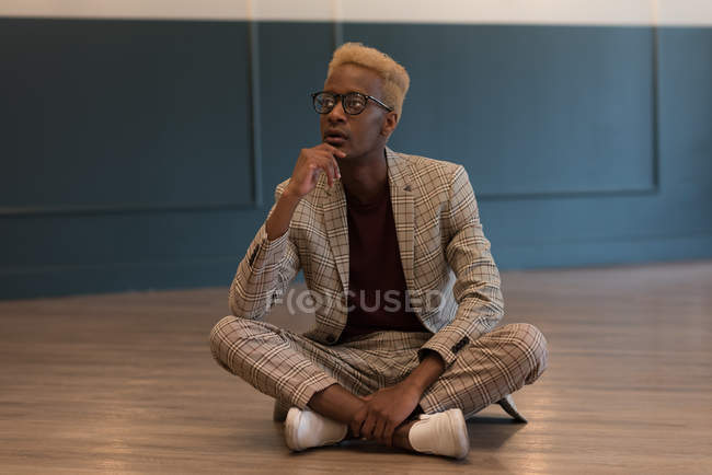 Задумчивый бизнесмен сидит на полу в офисе — стоковое фото