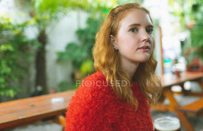 Redhead woman holding a glass of beer in outdoor cafe — Stock Photo