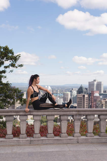 Female jogger relaxing on railing on a sunny day — Stock Photo