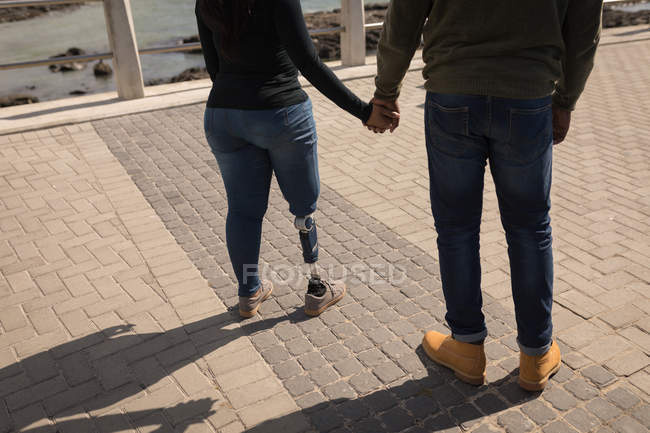 Низкая часть пары, держащихся за руки на набережной — стоковое фото