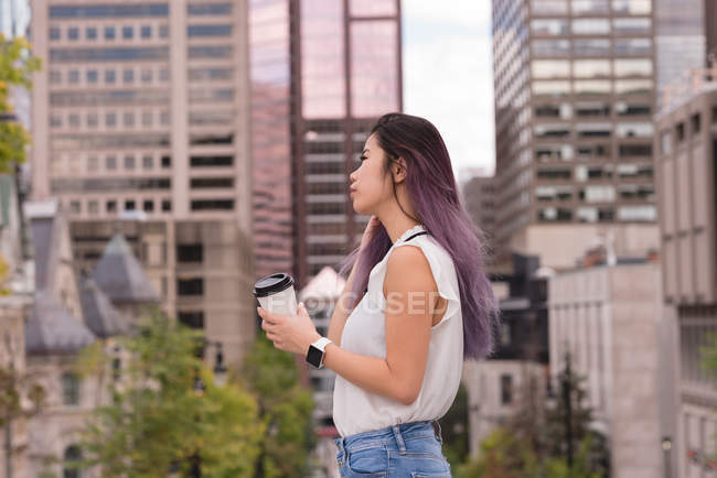 Belle femme tenant tasse de café dans la rue — Photo de stock