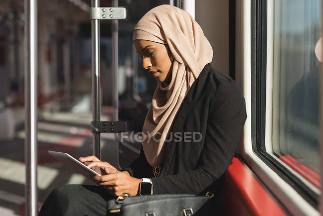 Mulher hijab a utilizar comprimido digital enquanto viaja de comboio — Fotografia de Stock