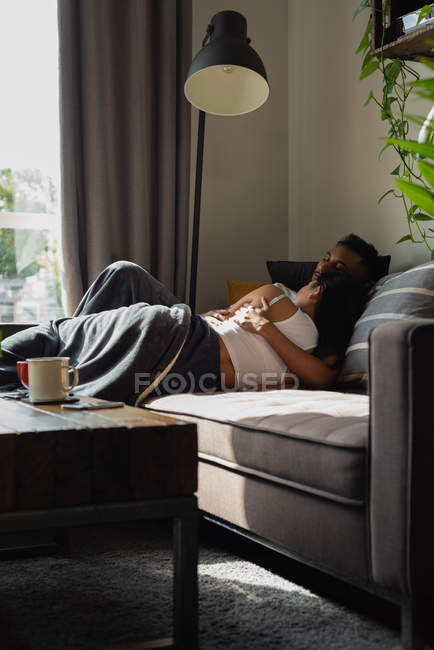 Couple lying on sofa in living room at home — Stock Photo