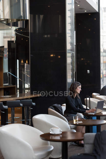 Vista lateral da mulher de negócios usando laptop no hotel — Fotografia de Stock
