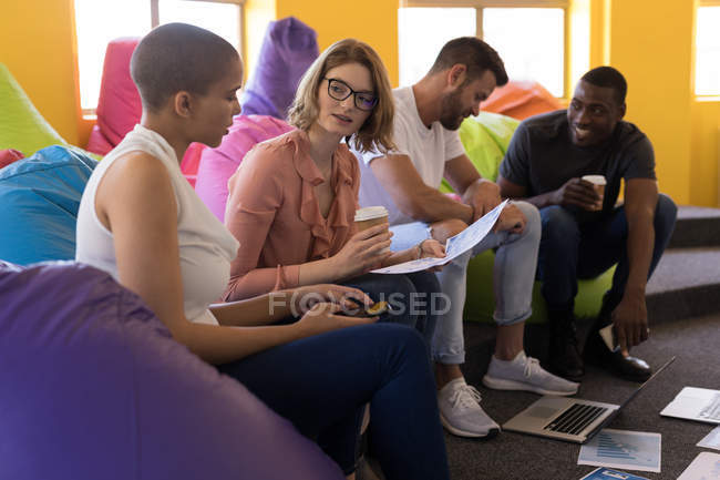 Business executives working while sitting on beanbag in office — Stock Photo
