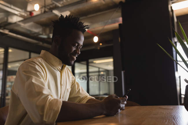 Executivo masculino usando telefone celular no refeitório no escritório — Fotografia de Stock