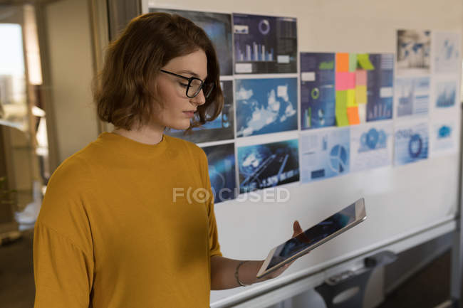 Young female executive using digital tablet in office — Stock Photo
