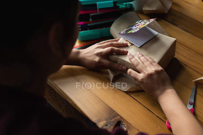 Woman wrapping gift box in living room at home — Stock Photo