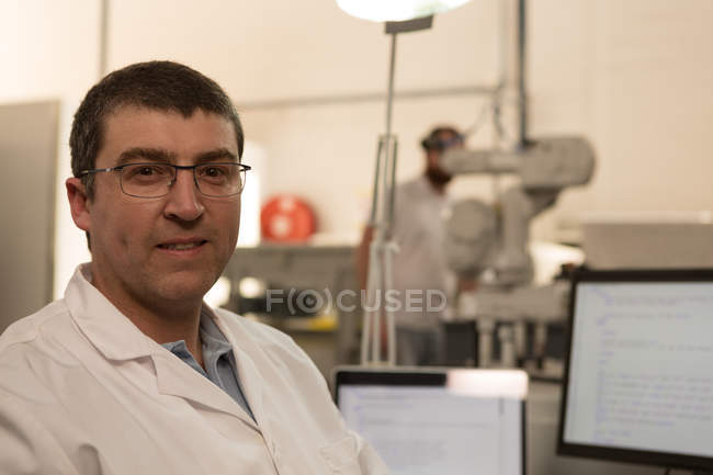 Porträt eines Roboteringenieurs, der in Lagerhalle in die Kamera blickt — Stockfoto