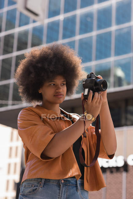Mujer haciendo clic en la foto con cámara digital en la ciudad - foto de stock