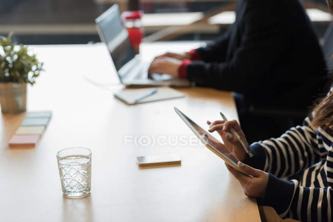 Seção média de executiva feminina usando tablet digital no escritório — Fotografia de Stock